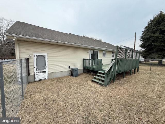 back of property with a shingled roof, fence, a deck, and central AC