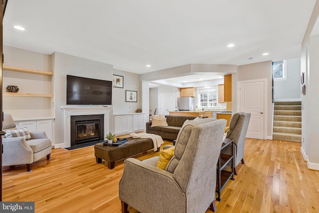 living room with stairs, plenty of natural light, and light wood-style floors