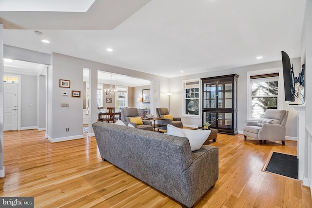 living area with light wood-style flooring, a notable chandelier, recessed lighting, and baseboards