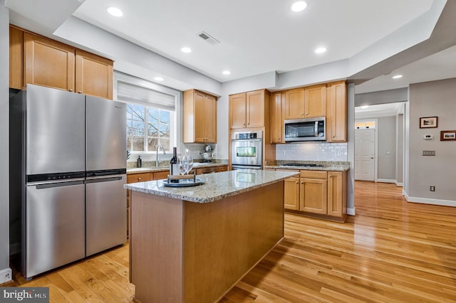 kitchen with visible vents, light wood-style flooring, appliances with stainless steel finishes, decorative backsplash, and light stone countertops