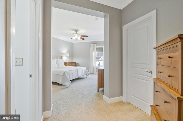 bedroom featuring light colored carpet, a ceiling fan, crown molding, and baseboards