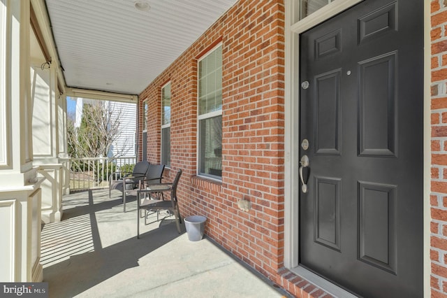 entrance to property featuring brick siding and a porch