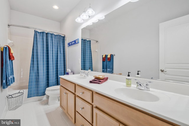 bathroom with a sink, toilet, double vanity, and tile patterned floors