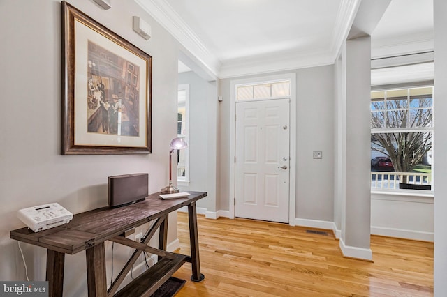 entrance foyer with a healthy amount of sunlight, light wood-type flooring, crown molding, and baseboards