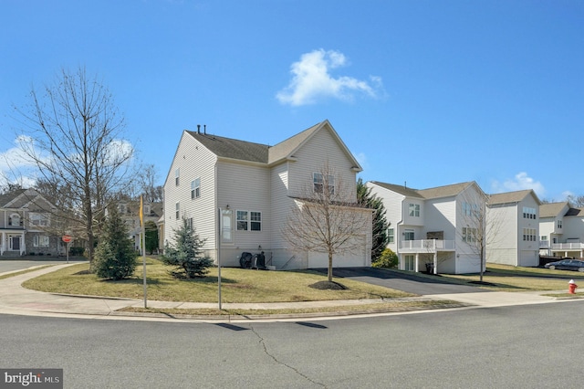 view of front of property featuring aphalt driveway, a residential view, and a front yard