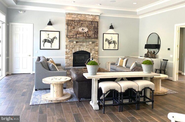 living area with baseboards, a stone fireplace, wood tiled floor, and crown molding