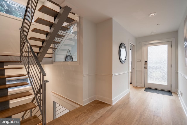 entryway featuring stairs, plenty of natural light, wood finished floors, and baseboards