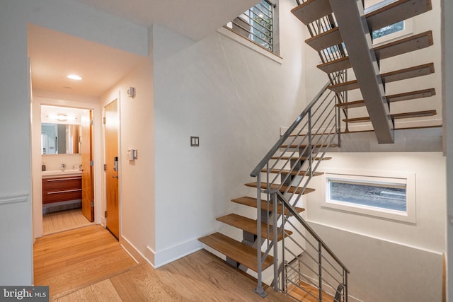 stairway with recessed lighting, wood finished floors, and baseboards