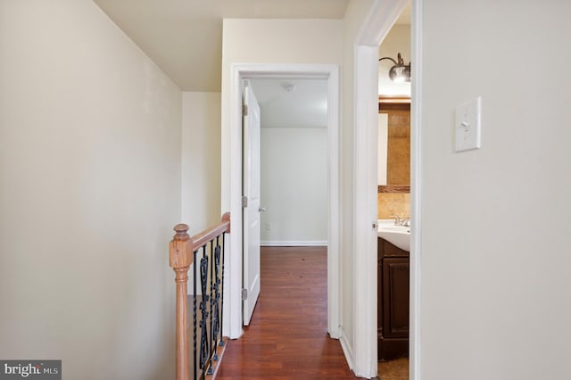 hallway featuring dark wood finished floors, an upstairs landing, and baseboards