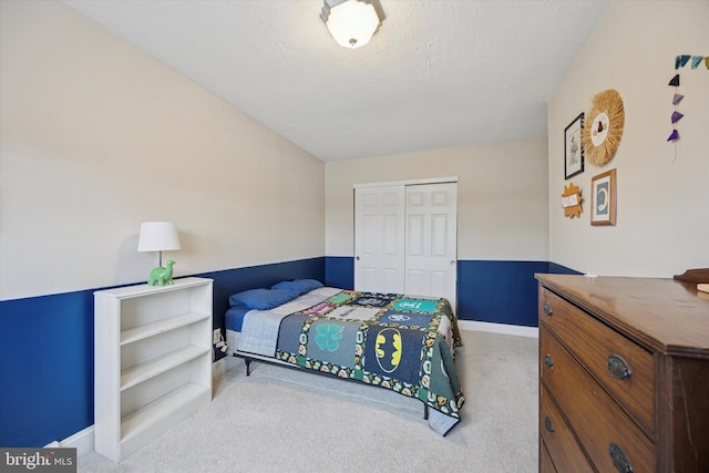 carpeted bedroom featuring a textured ceiling, baseboards, and a closet