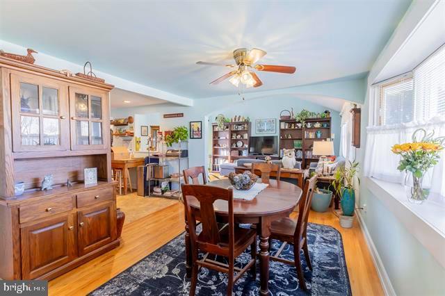 dining area with arched walkways, ceiling fan, light wood-style flooring, and baseboards