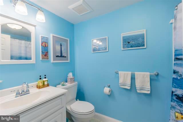 bathroom featuring toilet, baseboards, and vanity