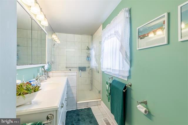 bathroom with visible vents, a shower stall, vanity, and tile patterned floors