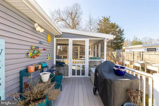 wooden terrace with a sunroom, a grill, and fence