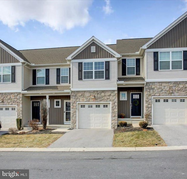 view of front of house featuring board and batten siding, concrete driveway, stone siding, and an attached garage