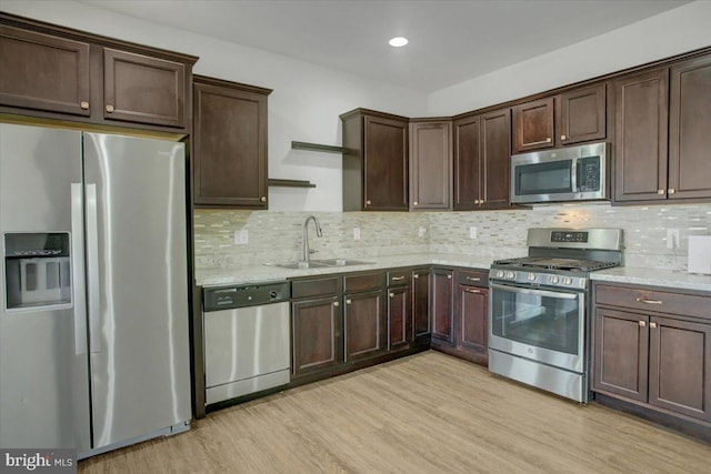 kitchen featuring stainless steel appliances, light wood-type flooring, a sink, and dark brown cabinetry