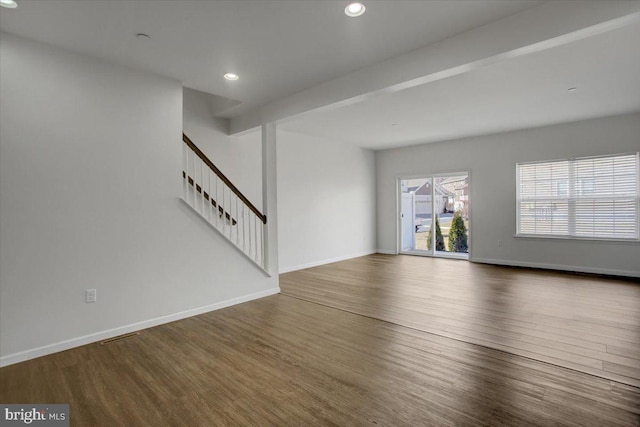 unfurnished living room with recessed lighting, wood finished floors, baseboards, stairs, and beam ceiling