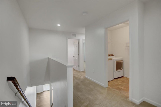 hallway featuring visible vents, independent washer and dryer, an upstairs landing, and light colored carpet