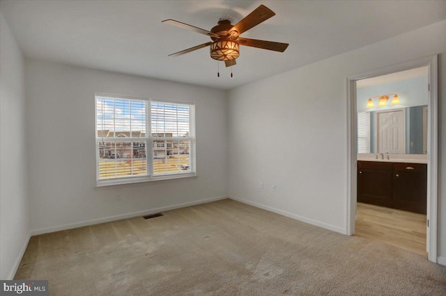 unfurnished bedroom with visible vents, baseboards, ensuite bathroom, and light colored carpet