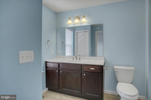 bathroom with toilet, baseboards, and vanity