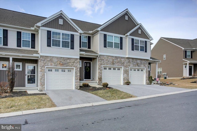 view of front of home featuring an attached garage, driveway, board and batten siding, and stone siding