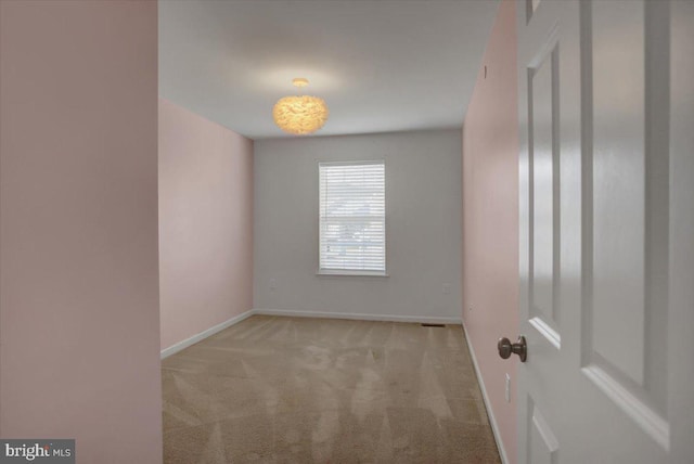 spare room featuring carpet flooring and baseboards