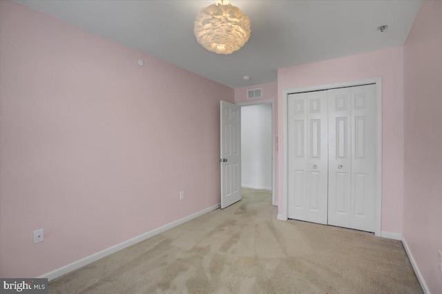 unfurnished bedroom featuring carpet, visible vents, baseboards, and a closet