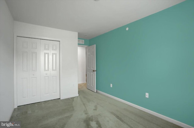 unfurnished bedroom with a closet, carpet, visible vents, and baseboards