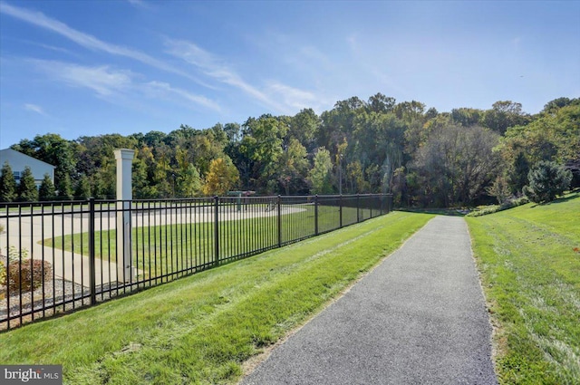 view of community featuring a forest view, a lawn, and fence