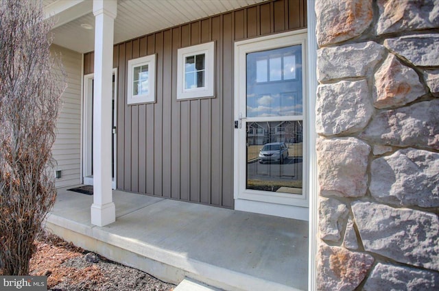 view of exterior entry featuring board and batten siding and covered porch