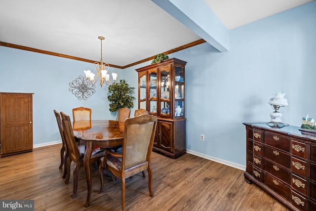 dining space with a notable chandelier, crown molding, baseboards, and wood finished floors