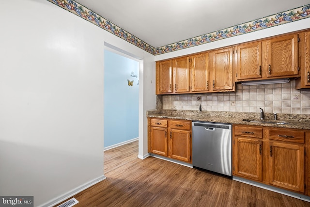 kitchen featuring a sink, tasteful backsplash, brown cabinets, and stainless steel dishwasher