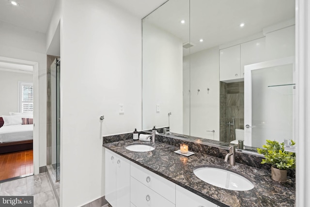 bathroom with double vanity, a sink, toilet, and a shower with door