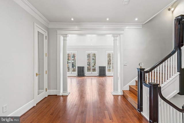 entryway featuring ornate columns, crown molding, baseboards, and hardwood / wood-style floors