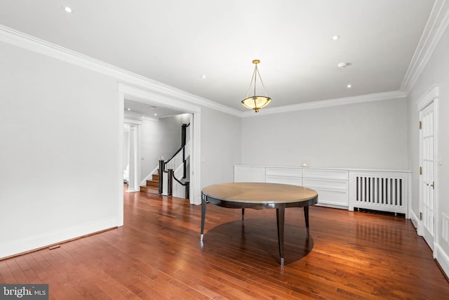 dining room with wood-type flooring, stairs, and crown molding