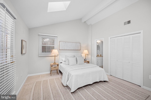 bedroom featuring visible vents, baseboards, lofted ceiling with skylight, carpet flooring, and ensuite bathroom