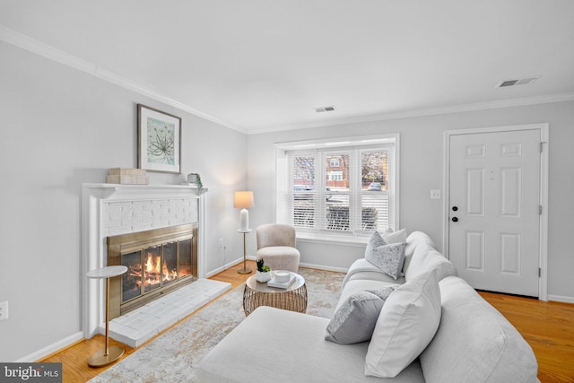 living room with a brick fireplace, wood finished floors, visible vents, and baseboards