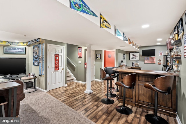 bar with recessed lighting, wood finished floors, baseboards, stairs, and a dry bar