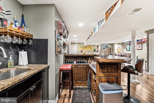 bar with wet bar, dark wood-style flooring, visible vents, and a sink