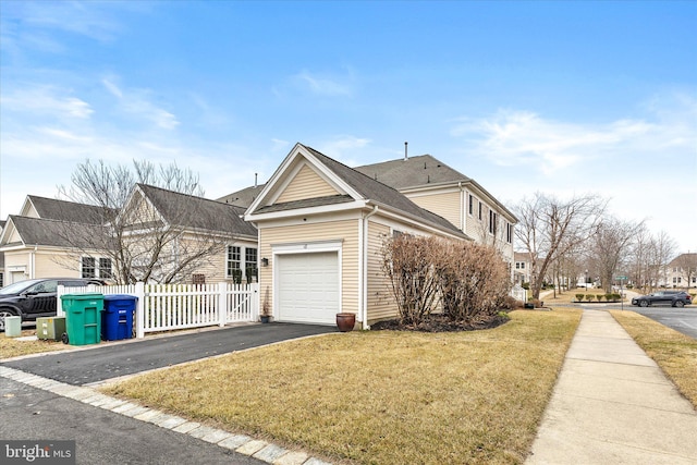 view of front of house with a garage, a residential view, aphalt driveway, fence, and a front lawn