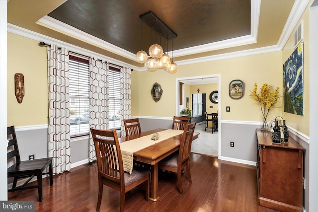 dining room featuring wood finished floors, a raised ceiling, and crown molding