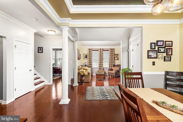 dining area featuring baseboards, crown molding, ornate columns, and wood finished floors