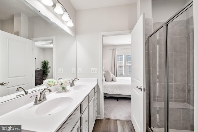 bathroom featuring a shower stall, wood finished floors, ensuite bathroom, and a sink