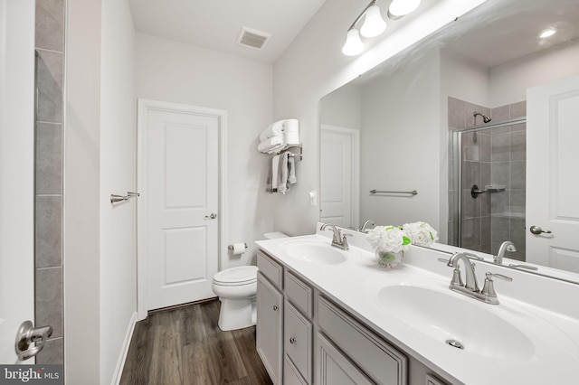 bathroom with a tile shower, visible vents, wood finished floors, and a sink