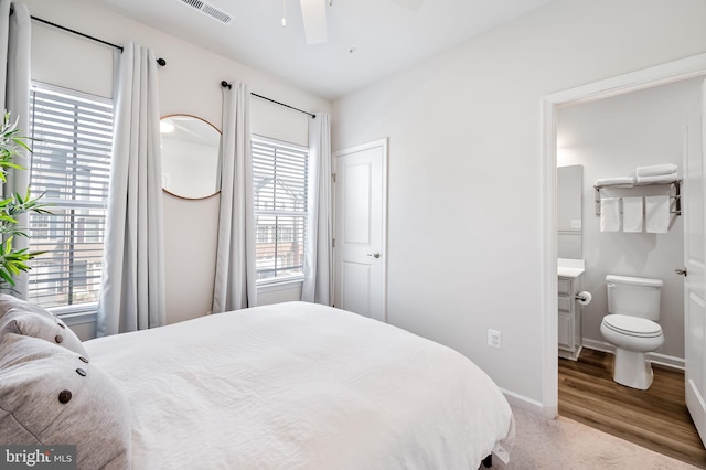 bedroom with visible vents, baseboards, wood finished floors, and ensuite bathroom