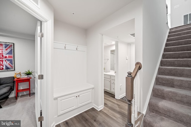 mudroom with wood finished floors, visible vents, and baseboards