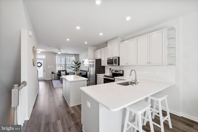 kitchen featuring a sink, a center island, light countertops, stainless steel appliances, and open shelves