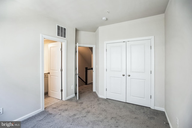 unfurnished bedroom with carpet floors, baseboards, visible vents, and a closet