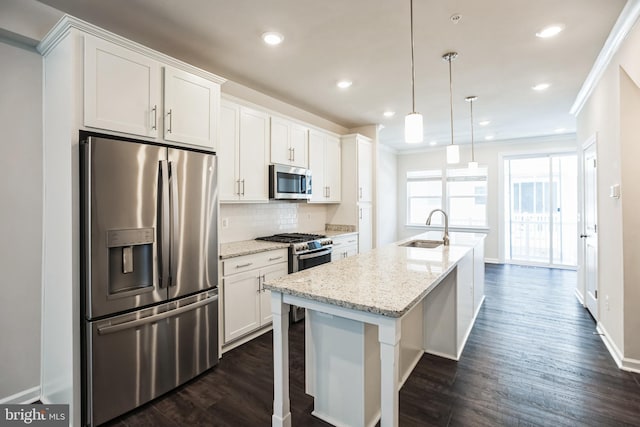 kitchen with stainless steel appliances, white cabinets, a sink, and a center island with sink