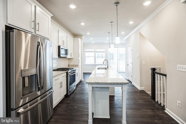 kitchen with a center island with sink, stainless steel appliances, tasteful backsplash, white cabinets, and a sink